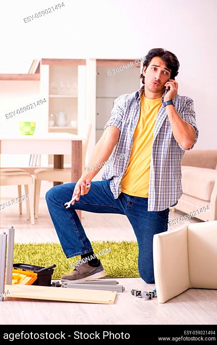 Young handsome man repairing chair at home