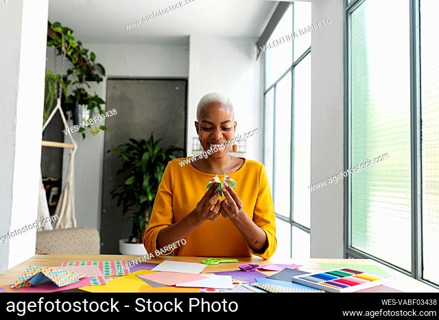Origami artist sitting in studio working with colorful paper