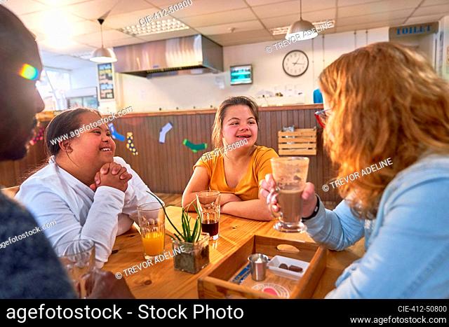 Young women with Down Syndrome talking with mentors in cafe