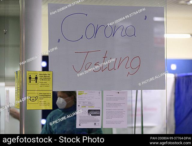 03 August 2020, Saxony, Dresden: An employee of the Association of Statutory Health Insurance Physicians of Saxony is standing behind a sign saying ""Corona...