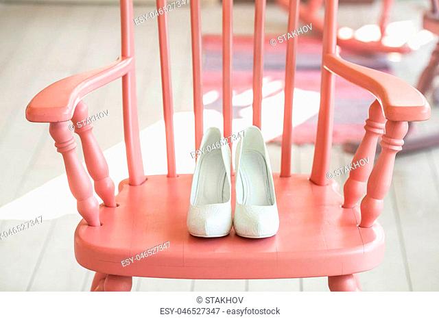 Womens wedding shoes on pink wooden chair. Close-up