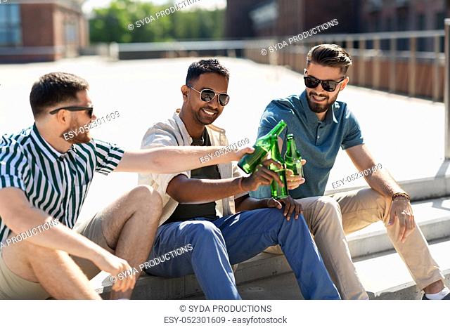 happy male friends drinking beer on street