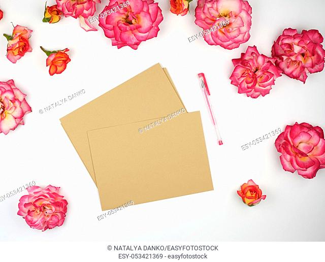 pink rose buds and a brown paper envelope on a white background, flat lay