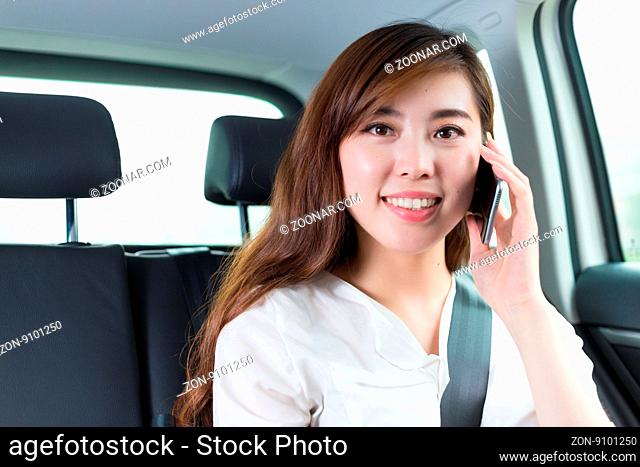 young beautiful asian girl with phone in car