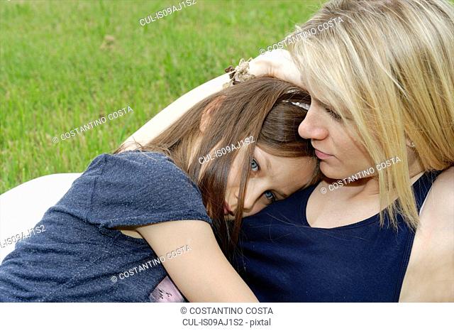 Close up of girl and mother hugging in park