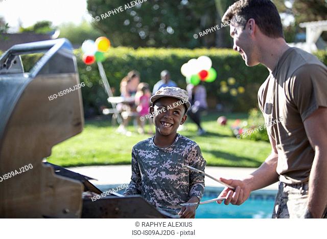 Male soldier and boy barbecuing at homecoming party