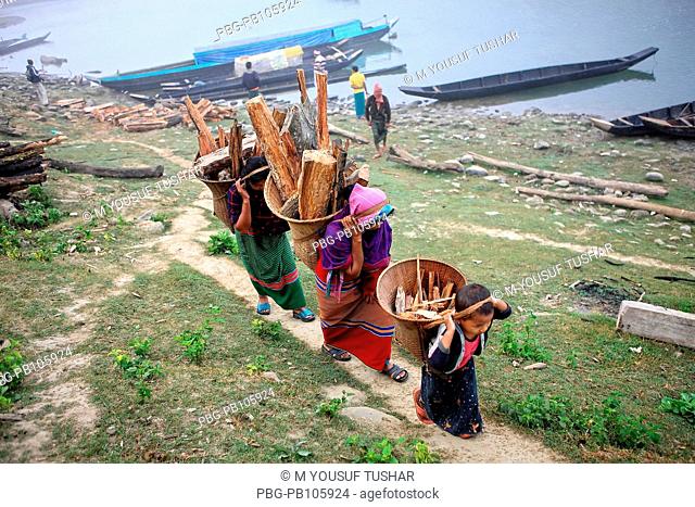 Ethnic Marma women carry basket of firewoods on their backs at the bank of Sangu river at Thanchi Bandarban, Bangladesh December 2009