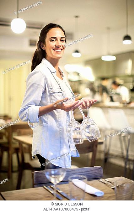 Waitress setting table at restaurant, portrait