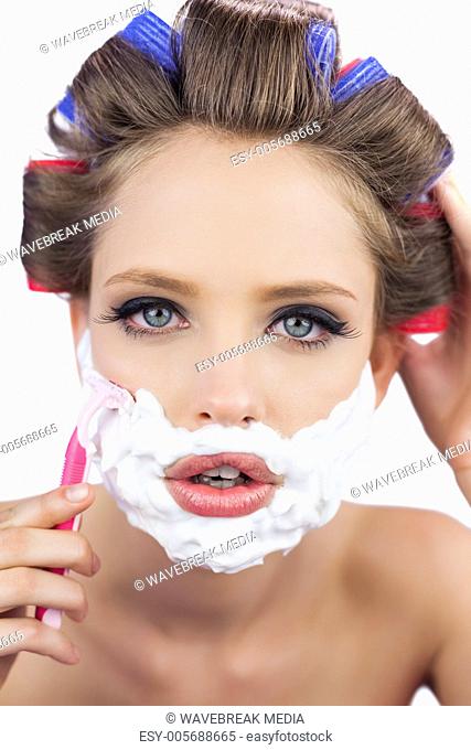Model in hair curlers posing with shaving foam and razor in close up