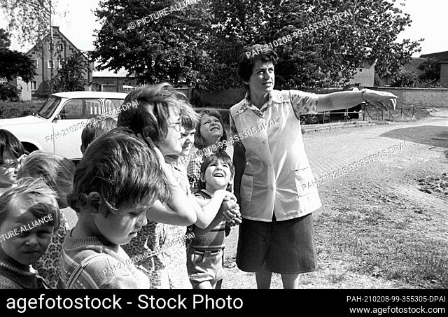 30 November 1983, Saxony, Kyhna: Kindergarten children are with their kindergarten teacher in the early 1980s in a village in the district of Delitzsch and look...