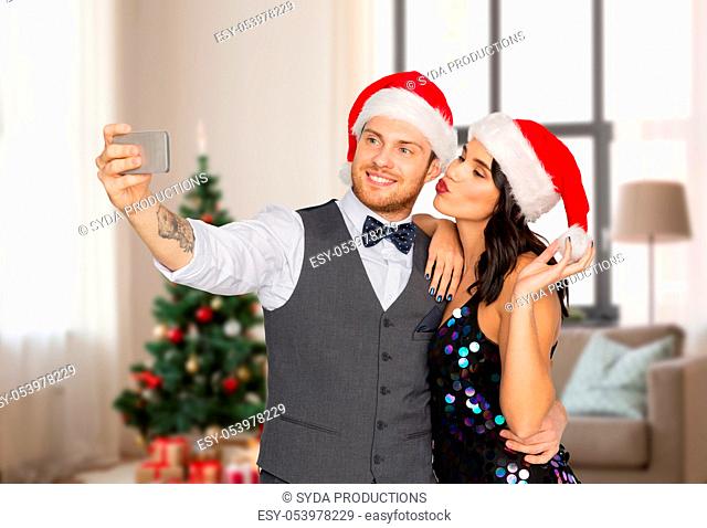 couple in santa hats taking selfie on christmas