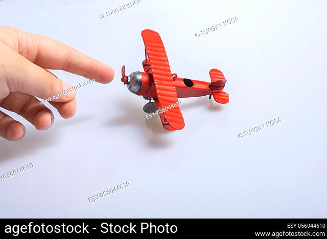 Hand holding a red toy plane on a black background