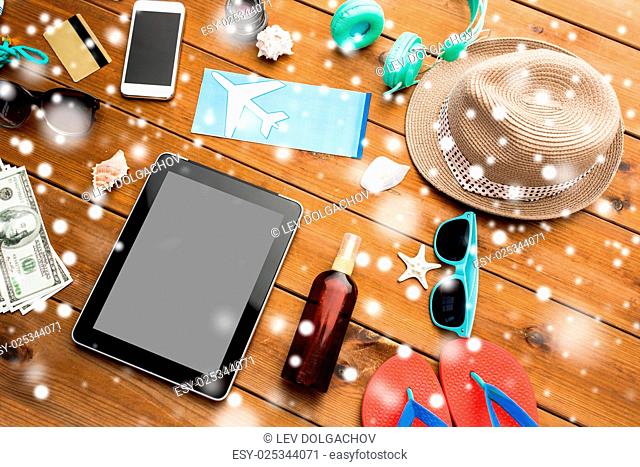 vacation, winter holidays, tourism and technology concept - tablet pc computer, airplane ticket and travel stuff over snow