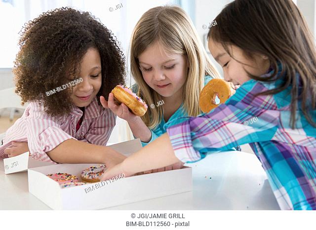 Girls eating donuts together in kitchen