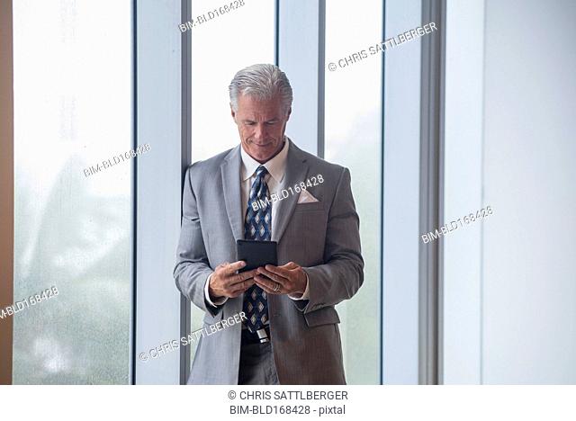 Caucasian businessman using digital tablet near window