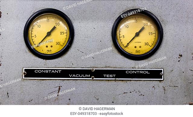 Vintage antique automotive machine shop vacuum gauges on a silver sheet metal plate with sign