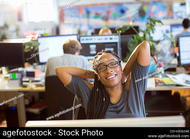 Portrait confident businesswoman stretching in open plan office