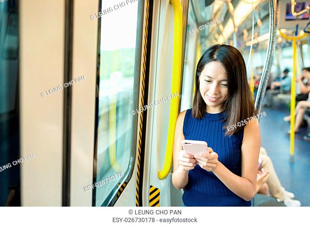 Woman sending text message inside train compartment