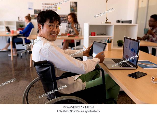 Disabled male executive using digital tablet at desk