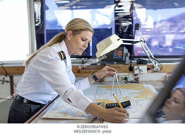 Female deck officer working on a nautical map