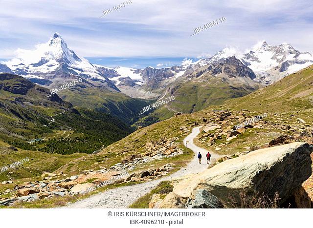 Two hikers on a trail to Stellisee lake, at the back the mountains Matterhorn, Dent Blanche, Obergabelhorn and Wellenkuppe, Zermatt, Canton of Valais