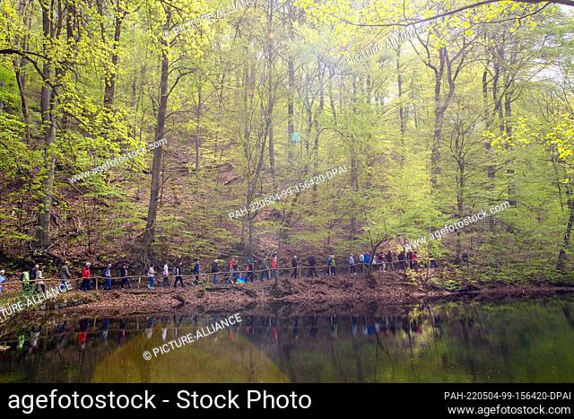 04 May 2022, Saxony-Anhalt, Bad Suderode: Participants of the ""Hike with Heart's Blood"" walk past a lake. The ""Hike with Heart's Blood"" was organized by the...