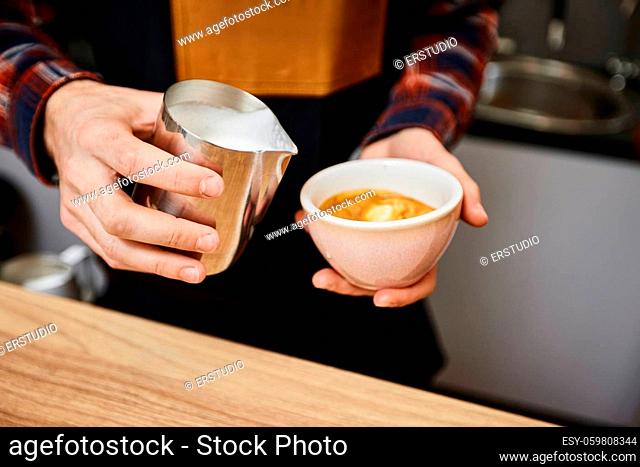 Caucasian man pouring hot milk in coffee. small business concept