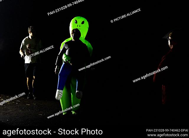 28 October 2023, Berlin: A runner takes part in the Halloween Run Berlin 2023 with inflated alien figure. The course leads through the Volkspark Jungfernheide