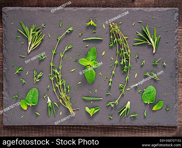 Fresh raw green herbs leaf - mint, rosemary, thyme - over gray stone background. Flat lay or top view