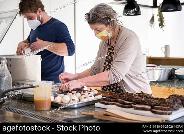 22 January 2021, Bavaria, Nuremberg: Gabriele Hussenether, owner of the Mobile Kochkunst cooking school, prepares ordered dishes for takeaway with her chef...