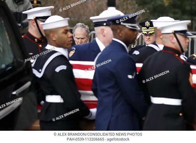 Former president George W. Bush watches as the flag-draped casket of former President George H.W. Bush is carried by a joint services military honor guard into...