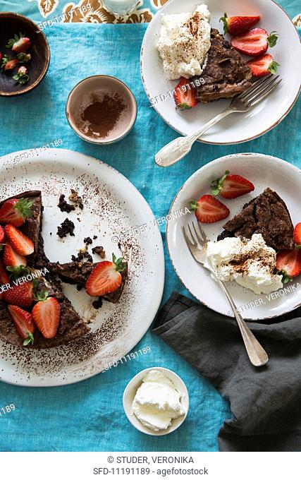 A small chocolate cake with fresh strawberries and cream
