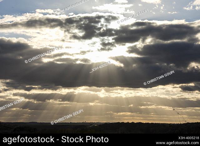 Countryside landscape under a cloudy sky pierced by rays of the sun, Eure-et-Loir department, Centre-Val-de-Loire region, France, Europe