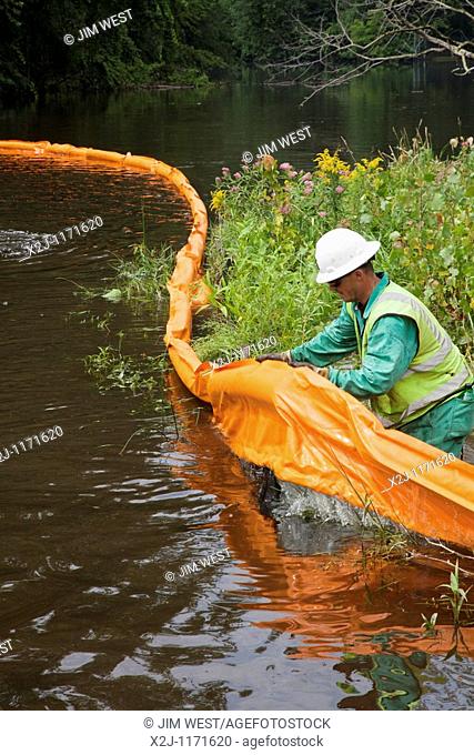Battle Creek, Michigan - A worker places containment boom on the Kalamazoo River to contain an oil spill  More than 800, 000 gallons of oil spilled from an...
