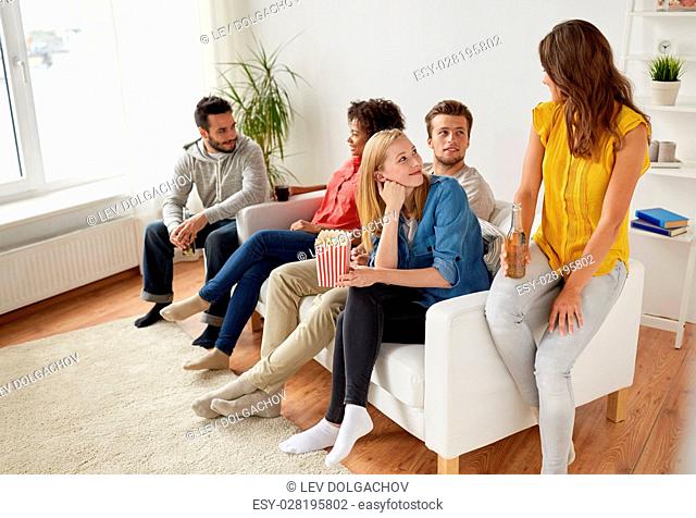 friendship, people and communication concept - happy friends with popcorn and beer talking at home