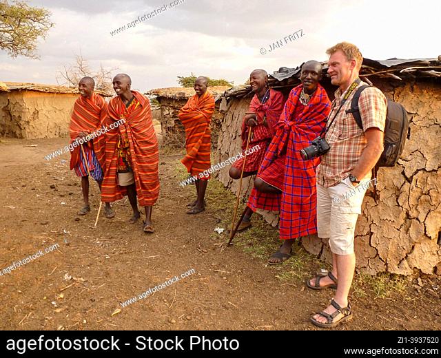 tourist and group of Masai men in Masai village in Masai Mara, Kenya