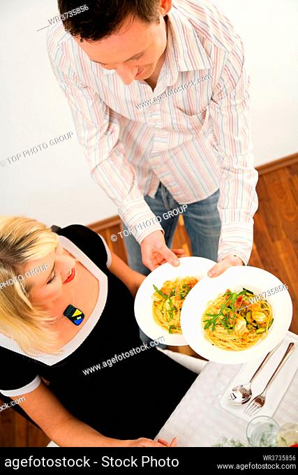 Young couple romantic dinner: he shows her what he has cooked - pasta