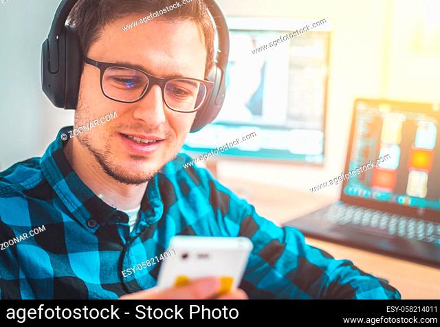 Young Caucasian man with headphones sitting on his workplace, entrepreneur