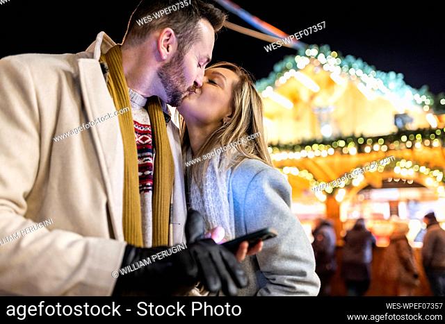 Young woman kissing man at Christmas market