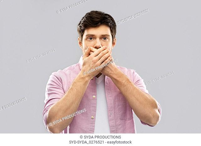 shocked young man covering his mouth by hands