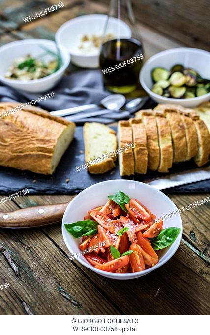 Bruschetta and various ingredients, bread and tomato with basil in a bowl