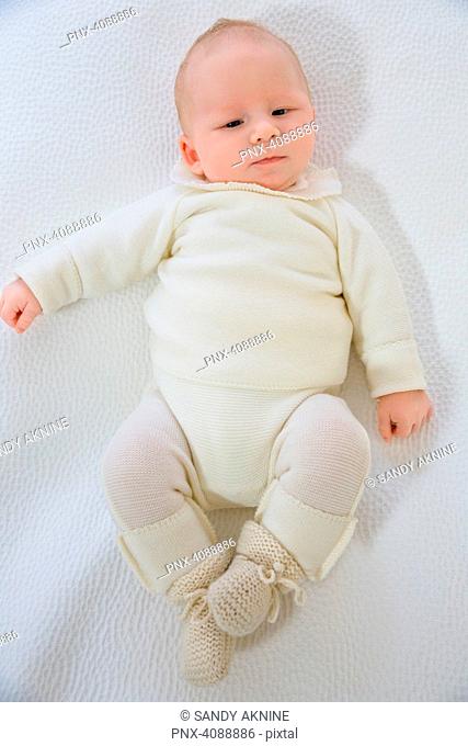 Top view of a baby of 2 months in white layette lying on the back