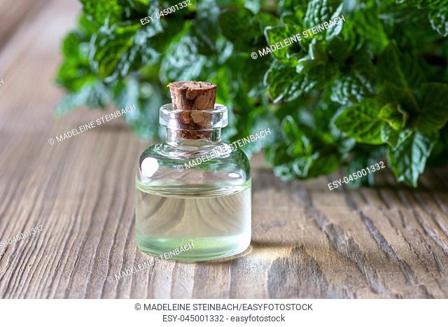 A bottle of essential oil with fresh peppermint leaves in the background