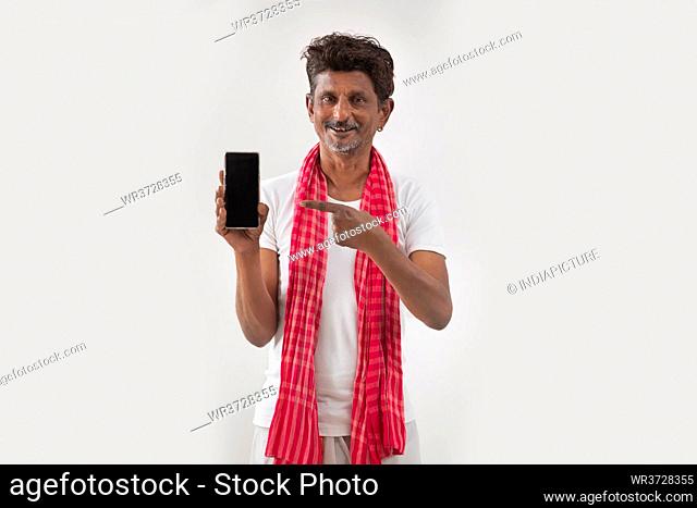 PORTRAIT OF A RURAL MAN holding mobile phone and pointing