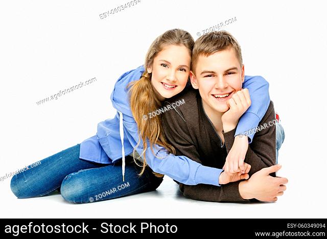 Beautiful teenage girl and boy in casual clothes sitting over white background. Isolated. Copy space