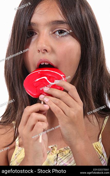 Young girl eating a red lollypop