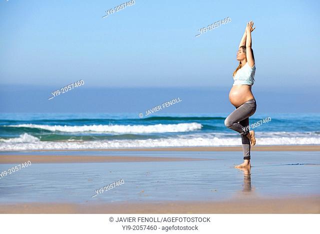 pregnant woman doing exercise on the beach
