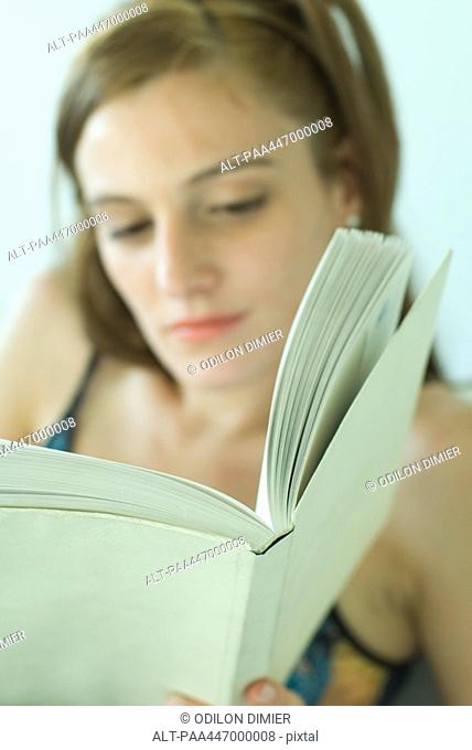 Young woman reading, focus on book