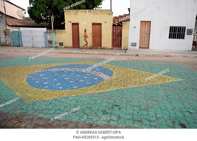 A woman passes a Brazilian flag painted onto the street in a village near Porto Seguro in Brazil, 09 June 2014. The German national soccer team stays in a hotel...