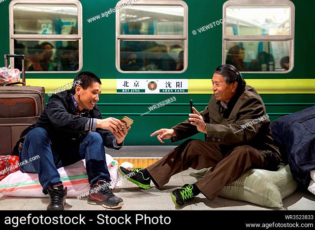 Two men watch phone in the train on the platform